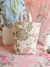 Decorative tote bag with floral pattern on a pink floral background