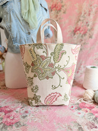 Decorative tote bag with floral pattern on a pink floral background